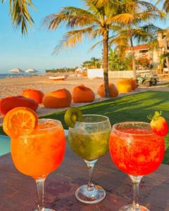 three cocktails in wine glasses on a table near the beach at Pousada Casa Canto das Águas in Icaraí