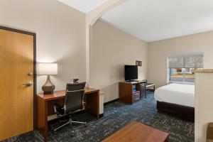 a hotel room with a bed and a desk with a computer at Comfort Suites Kansas City-Liberty in Liberty