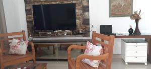 sala de estar con 2 sillas y TV de pantalla plana en Casa da Tôta en São João Batista do Glória