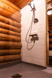 a shower in a room with a wooden wall at Suvituuli in Kuusamo
