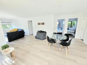 sala de estar con mesa de cristal y sillas en Hosts on the Coast - Catherine Chic, en Whitianga