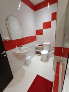a red and white bathroom with a sink and a toilet at SeaWaves Apartments in Xgħajra