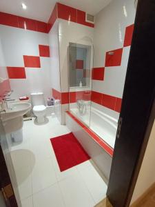 a red and white bathroom with a toilet and a shower at SeaWaves Apartments in Xgħajra