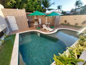 a swimming pool with an umbrella and a table and chairs at MAKARANDUBA BEACH 304 - Piscinas Naturais e Coração de Porto in Porto De Galinhas