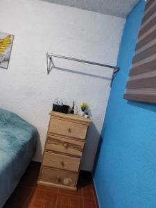 a bedroom with a dresser and a blue wall at Visita Pachuca junto a familia , 2 Recamaras 1- cama ks , Recamara 2 -1 Cama KS , baño privado , 1 Comedor (Refrigerador, desayunador, estufa ) in Pachuca de Soto