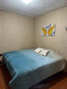 a bedroom with a bed with a painting of butterflies at Visita Pachuca junto a familia , 2 Recamaras 1- cama ks , Recamara 2 -1 Cama KS , baño privado , 1 Comedor (Refrigerador, desayunador, estufa ) in Pachuca de Soto