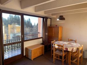尚魯斯的住宿－Studio Cabine Chamrousse，一间带桌子的用餐室和一个阳台