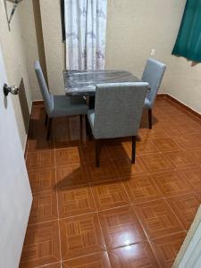 a dining room table and chairs with a wooden floor at Visita Pachuca junto a familia , 2 Recamaras 1- cama ks , Recamara 2 -1 Cama KS , baño privado , 1 Comedor (Refrigerador, desayunador, estufa ) in Pachuca de Soto