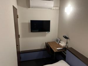 a hotel room with a desk with a television on the wall at GUEST HOUSE MASAGO - Vacation STAY 13810v in Urakawa