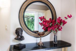 a mirror on a shelf with flowers and a bust at Sanctuary Palms in Paihia