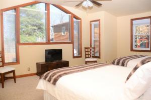 1 dormitorio con 1 cama, TV y ventanas en Bent Mountain Lodge en Roanoke