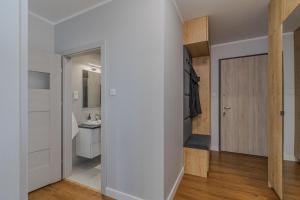 a room with a white wall and a bathroom at Glow Apartments, Apartamenty Nowa Letnica in Gdańsk