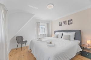 ein weißes Schlafzimmer mit einem Bett und einem Stuhl in der Unterkunft FEEL HOME Apartments in Schönaich