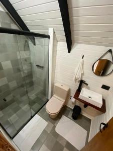 een badkamer met een douche, een toilet en een wastafel bij chalé Platanus in Campos do Jordão