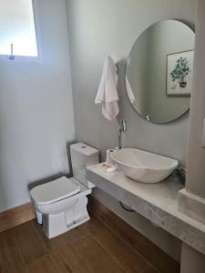 ein Badezimmer mit einem Waschbecken, einem WC und einem Spiegel in der Unterkunft Casas de alto padrão em Condominio Privado in Chapada dos Guimarães