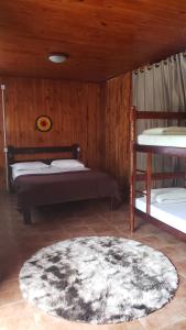 a bedroom with two bunk beds and a rug at Wood house casa privada in Abraão