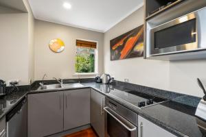 a kitchen with a sink and a microwave at Sanctuary Palms in Paihia +28 photos
