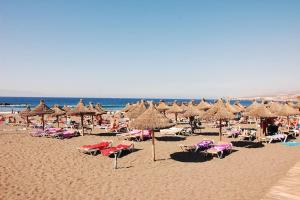 a beach with many chairs and umbrellas and the ocean at Amazing Penthouse in Los Cristianos