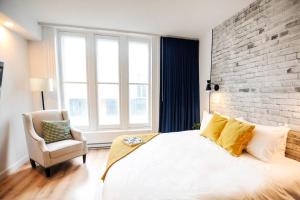 een slaapkamer met een wit bed en een bakstenen muur bij The Old Fashioned Downtown Qc in Québec