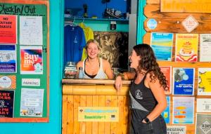 dos mujeres de pie en un mostrador en un bar en ITH Beach Bungalow Surf Hostel San Diego, en San Diego