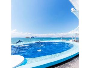 Zentsuji Grand Hotel - Vacation STAY 16623v في Zentsuji: مسبح فيه دلافين تقفز في الماء