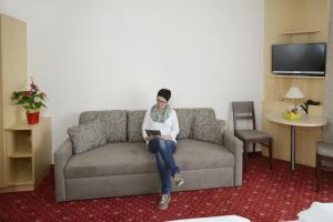 a woman sitting on a couch with a tablet at Kutscherwirt in Vorau
