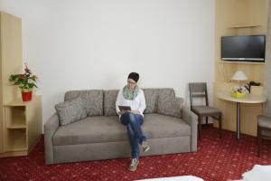 uma mulher sentada num sofá com um tablet em Kutscherwirt em Vorau