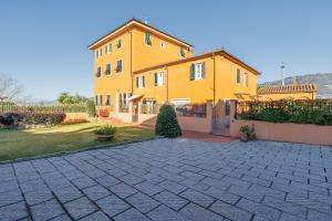 une grande maison jaune avec une allée en briques dans l'établissement Villa Petri, à Uzzano