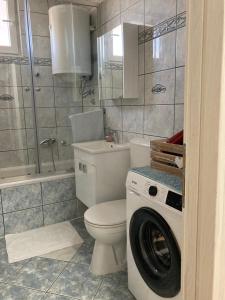 a bathroom with a toilet and a washing machine at Apartman Palac in Grude