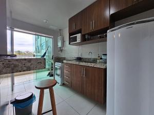 a kitchen with wooden cabinets and a white refrigerator at AP encantador na Praia do Forte! Porto Azul (106) in Cabo Frio