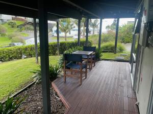 un patio con mesa y sillas en un porche en The Pacific Room, Tapeka Point, en Russell