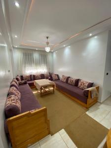 ein Wohnzimmer mit einem Sofa und einem Tisch in der Unterkunft Appartement avec suite parentale in Mohammedia