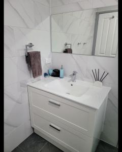 Baño blanco con lavabo y espejo en Blue Wren BnB Bathurst, en Bathurst