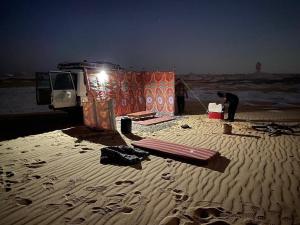 Un uomo in piedi di fronte a una tenda sulla spiaggia di White desert & Black desert camb a Qasr Al Farafirah