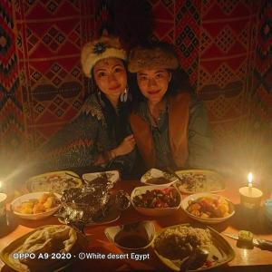 two women sitting at a table with food at White desert & Black desert camb in Qasr Al Farafirah