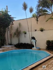 ein Schwimmbad mit einer Delfinstatue im Hof in der Unterkunft Flat Aconchego das Meninas in Porto De Galinhas