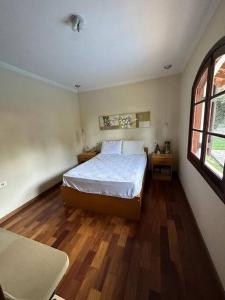 1 dormitorio con cama, suelo de madera y ventana en Recanto de Mairiporã, en Mairiporã