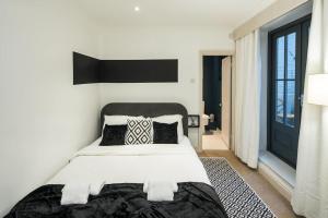a bedroom with a white bed with a black headboard at Superb Retreat Central Next Tube in London