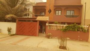 a house with a red gate in front of it at Lowéne in Guediawaye