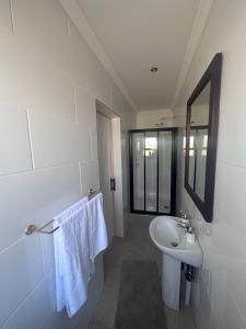 ein weißes Badezimmer mit einem Waschbecken und einem Spiegel in der Unterkunft The Edge Lodge in Polokwane