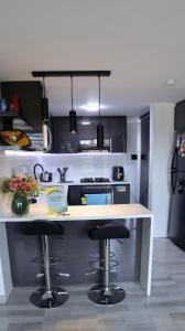 eine Küche mit einer Theke und 2 Barhockern in der Unterkunft TOCANCIPÁ, Increíble, Hermoso y Moderno APARTAMENTO COMPLETO! in Tocancipá