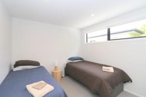 two beds in a white room with a window at Urban Cube in Invercargill