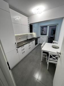 une cuisine avec des placards blancs et une table blanche dans l'établissement Amelia Apartment, à Braşov