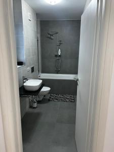 La salle de bains est pourvue d'un lavabo, de toilettes et d'une baignoire. dans l'établissement Amelia Apartment, à Braşov