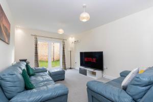 a living room with a blue couch and a tv at Supreme House in Middlesbrough