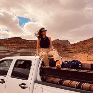 een vrouw die achterop een vrachtwagen zit bij Miral Night Camp in Wadi Rum