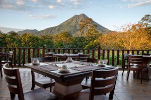 a table with chairs and a mountain in the background at Arenal Manoa Resort & Hot Springs in Fortuna