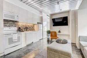 a kitchen with white cabinets and a couch and a tv at KCM Mikros Smart Apartments 6 in Cleveland