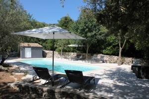 zwei Stühle und ein Sonnenschirm neben einem Pool in der Unterkunft LES GITES DE VALERIE Appartement de 50m2 avec parking privé in Nîmes