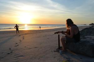 Eine Frau, die bei Sonnenuntergang am Strand Cricket spielt in der Unterkunft Castaways Nicaragua in Popoyo